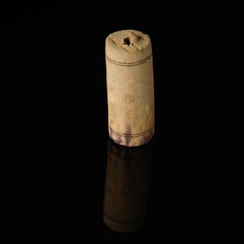 A close-up shot of a wine cork on a reflecting surface.