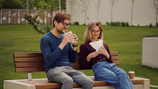 Young business people having a snack with takeaway food in a park. Eating outdoors. Enjoying food. Smells good snacks.