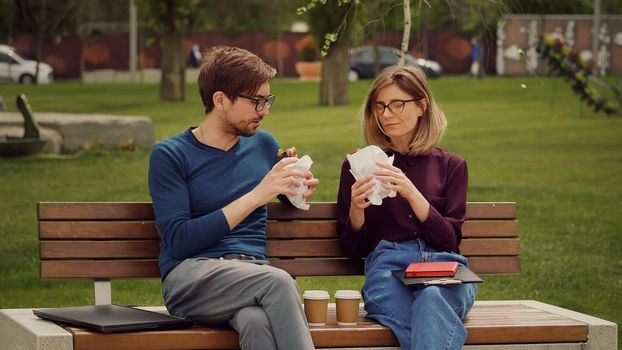 Hungry young business man enjoy a snack. Eat outdoors. Friends having a packed snack in a park. Friends eats with gusto.