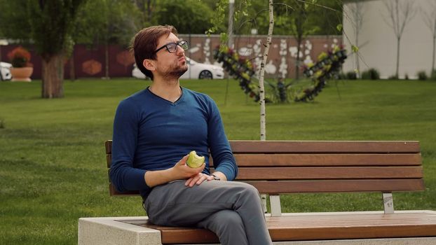 Handsome Man Eating Heathy food. Apple as Healthy Snack. Enjoying an fruit. Male Portrait have snack in park.