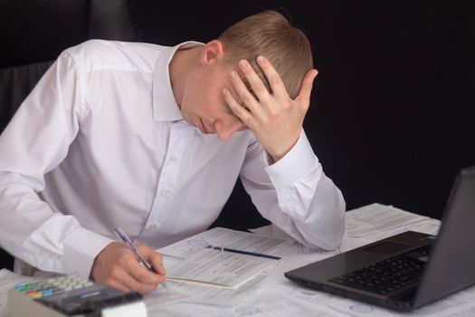 A businessman works with stocks, bonds, obligations, securities and documents in a night office. Fulfillment of obligations to work with documents in the office. Employee at a laptop in the office.