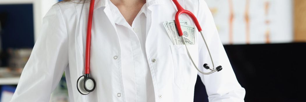 Close-up of head doctor in clinic with bunch of money in pocket of medical gown. Prestigious job position in clinic, earn good money. Career growth concept