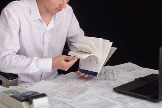 A businessman works with stocks, bonds, obligations, securities and documents in a night office. Fulfillment of obligations to work with documents in the office. Employee at a laptop in the office.