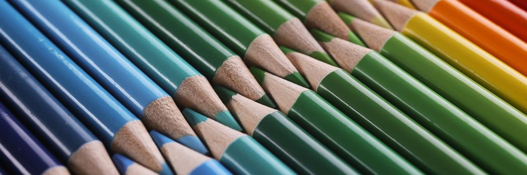 Close-up of colourful childrens drawing pencils pointing one another in line. Same colours fit each other, perfectionist vision. Anti-stress, art concept