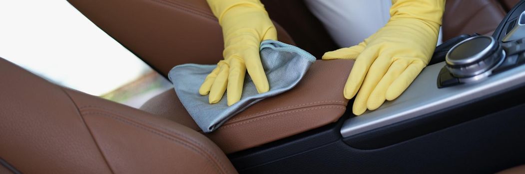 Close-up of person in protective gloves and uniform clean automobile with antibacterial cloth. Cleaning to prevent covid virus spread. Disinfection concept