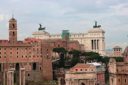 ROME, ITALY - February 05, 2022: Panoramic view around the Colosseum in city of Rome, Italy. Cold and gray sky in the background. Macro photography of the green parks with the old buildings.