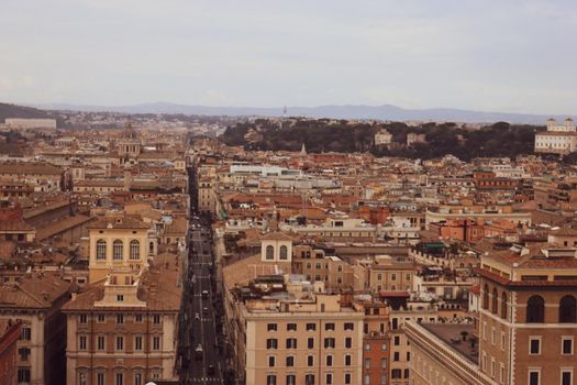 ROME, ITALY - February 05, 2022: Panoramic view around the Colosseum in city of Rome, Italy. Cold and gray sky in the background. Macro photography of the green parks with the old buildings.