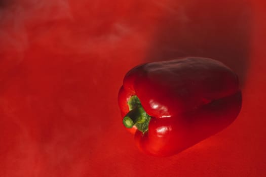 SWEET, fresh RED PEPPER ON A RED BACKGROUND WITH A LIGHT SMOKE.