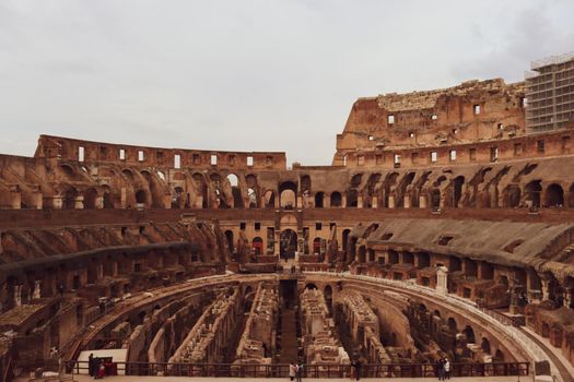 ROME, ITALY - February 05, 2022: Panoramic view around the Colosseum in city of Rome, Italy. Cold and gray sky in the background. Macro photography of the green parks with the old buildings.