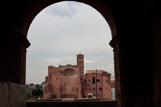 ROME, ITALY - February 05, 2022: Panoramic view around the Colosseum in city of Rome, Italy. Cold and gray sky in the background. Macro photography of the green parks with the old buildings.