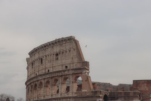 ROME, ITALY - February 05, 2022: Panoramic view around the Colosseum in city of Rome, Italy. Cold and gray sky in the background. Macro photography of the green parks with the old buildings.