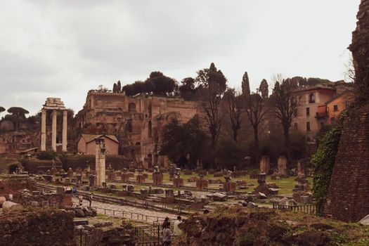 ROME, ITALY - February 05, 2022: Panoramic view around the Colosseum in city of Rome, Italy. Cold and gray sky in the background. Macro photography of the green parks with the old buildings.