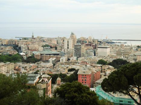 Genova, Italy - February 22, 2022: Evening view of Genoa (Genova) port, Italy with port cranes and industrial zone. Genoa, Italy. Lanterna lights by night. City illuminated behind the sea.