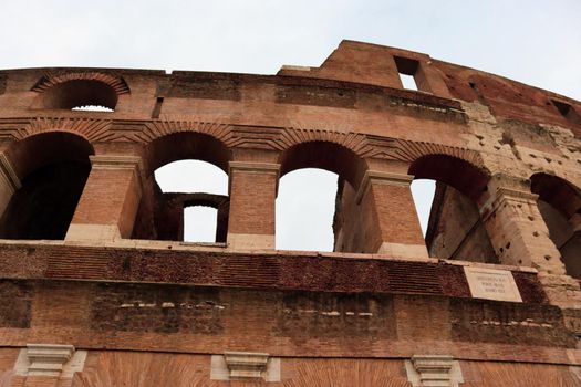 ROME, ITALY - February 05, 2022: Panoramic view around the Colosseum in city of Rome, Italy. Cold and gray sky in the background. Macro photography of the green parks with the old buildings.