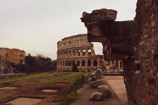 ROME, ITALY - February 05, 2022: Panoramic view around the Colosseum in city of Rome, Italy. Cold and gray sky in the background. Macro photography of the green parks with the old buildings.