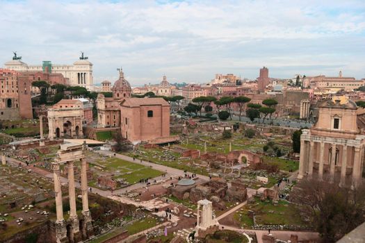 ROME, ITALY - February 05, 2022: Panoramic view around the Colosseum in city of Rome, Italy. Cold and gray sky in the background. Macro photography of the green parks with the old buildings.