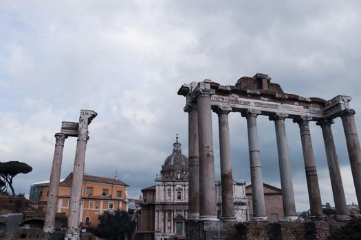 ROME, ITALY - February 05, 2022: Panoramic view around the Colosseum in city of Rome, Italy. Cold and gray sky in the background. Macro photography of the green parks with the old buildings.