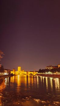 Genova, Italy - February 22, 2022: Evening view of Genoa (Genova) port, Italy with port cranes and industrial zone. Genoa, Italy. Lanterna lights by night. City illuminated behind the sea.