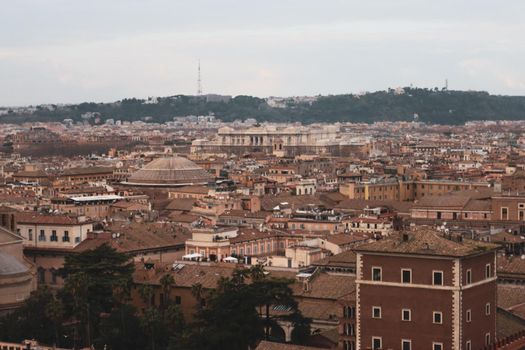 ROME, ITALY - February 05, 2022: Panoramic view around the Colosseum in city of Rome, Italy. Cold and gray sky in the background. Macro photography of the green parks with the old buildings.