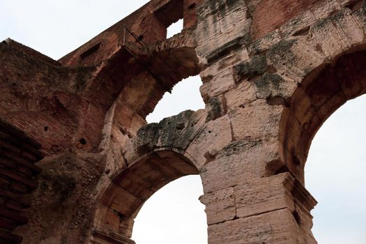 ROME, ITALY - February 05, 2022: Panoramic view around the Colosseum in city of Rome, Italy. Cold and gray sky in the background. Macro photography of the green parks with the old buildings.