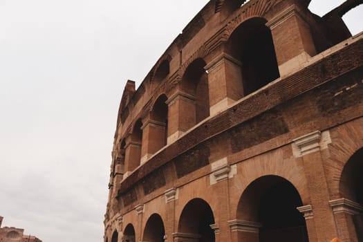 ROME, ITALY - February 05, 2022: Panoramic view around the Colosseum in city of Rome, Italy. Cold and gray sky in the background. Macro photography of the green parks with the old buildings.