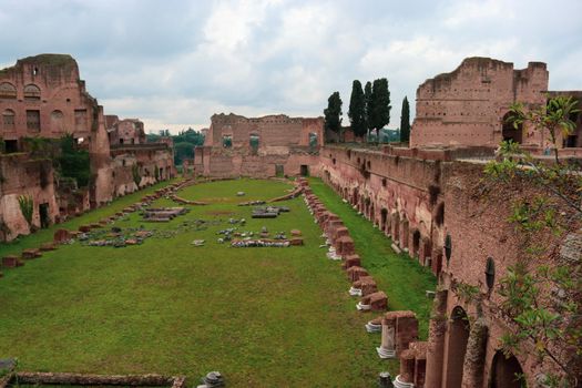 ROME, ITALY - February 05, 2022: Panoramic view around the Colosseum in city of Rome, Italy. Cold and gray sky in the background. Macro photography of the green parks with the old buildings.