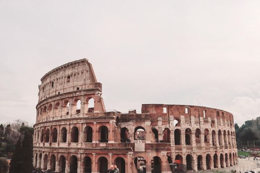 ROME, ITALY - February 05, 2022: Panoramic view around the Colosseum in city of Rome, Italy. Cold and gray sky in the background. Macro photography of the green parks with the old buildings.