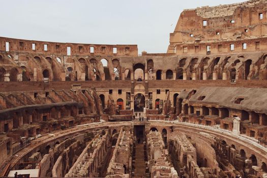 ROME, ITALY - February 05, 2022: Panoramic view around the Colosseum in city of Rome, Italy. Cold and gray sky in the background. Macro photography of the green parks with the old buildings.