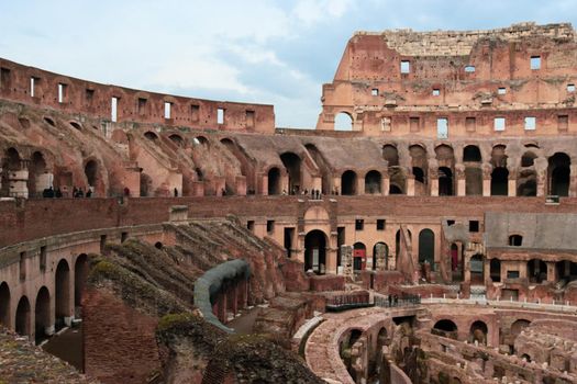 ROME, ITALY - February 05, 2022: Panoramic view around the Colosseum in city of Rome, Italy. Cold and gray sky in the background. Macro photography of the green parks with the old buildings.