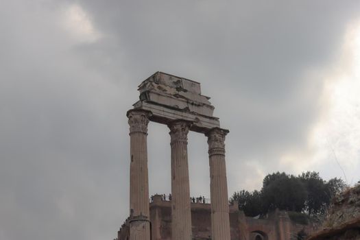 ROME, ITALY - February 05, 2022: Panoramic view around the Colosseum in city of Rome, Italy. Cold and gray sky in the background. Macro photography of the green parks with the old buildings.