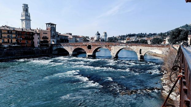 Verona, Italy - March 19, 2022: Aerial view of Verona historical city centre, Ponte Pietra bridge across Adige river, Verona Cathedral, Duomo di Verona, red tiled roofs, Veneto Region, Italy.