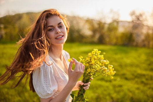 portrait of a woman with a bouquet of wild flowers in the rays of the setting sun in a field. High quality photo