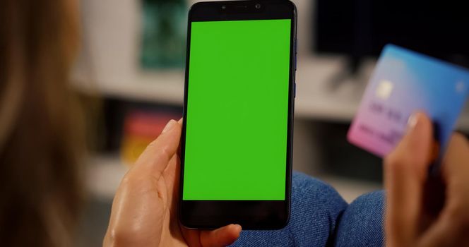 Woman Customer hands holding Credit Card and Smartphone with Chroma Key Green Screen. Close up view. Online Payment Concept. Shopping online.