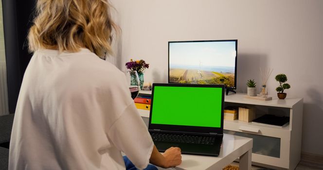 Caucasian Woman make web search on laptop with Greenscreen and Chroma Key. Mock Up with Tracking Markers and Alpha Matte. Female using laptop in living room.