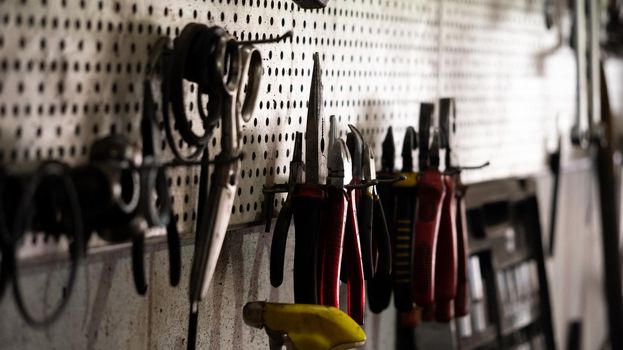 Pliers tools hanging on the wall. Different types of pliers in garage, workshop scene. Mechanical tools for working in the car repair service