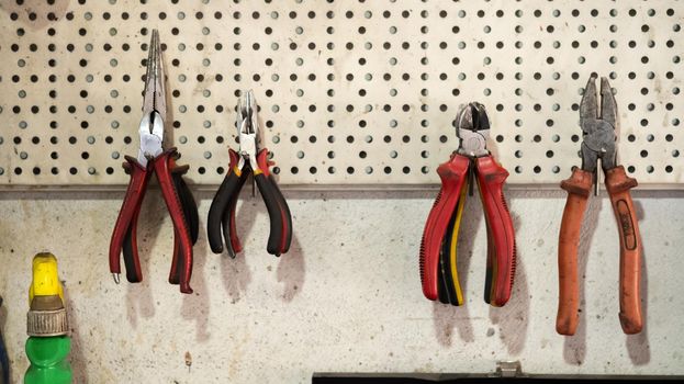 Pliers tools hanging on the wall. Different types of pliers in garage, workshop scene. Mechanical tools for working in the car repair service