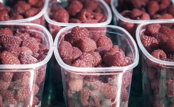 Ripe yellow and red raspberries in small containers for sale in the store.