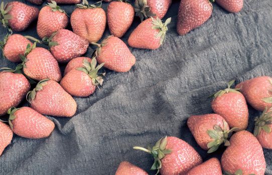 On the table on a linen napkin is a lot of berries ripe strawberries. Presented close-up with copy space.