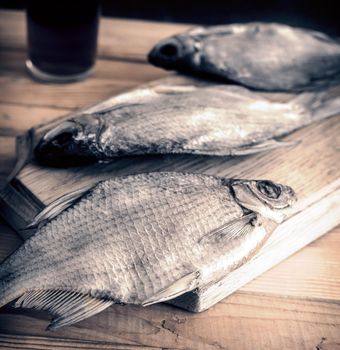 On a wooden table on a cutting Board dried fish, standing next to a glass of beer.