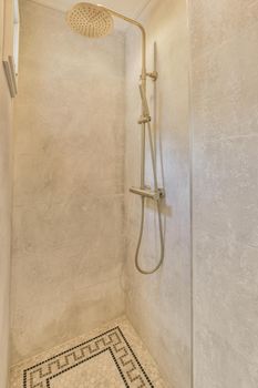 Shower faucets attached to tiled wall near glass partition and ornamental curtail in washroom at home