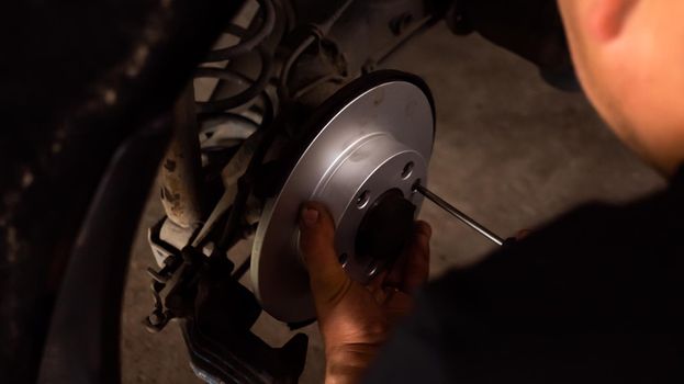 Disc Brake System Replacement Service. Mechanic hand changing car disc brake in garage