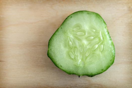 Cross-section of cucumber, top view, close-up, on a wooden background. Healthy food concept, natural product.
