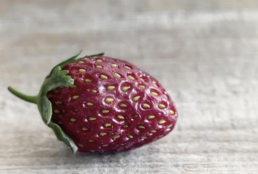 On wooden table one ripe strawberries. Presented close-up.