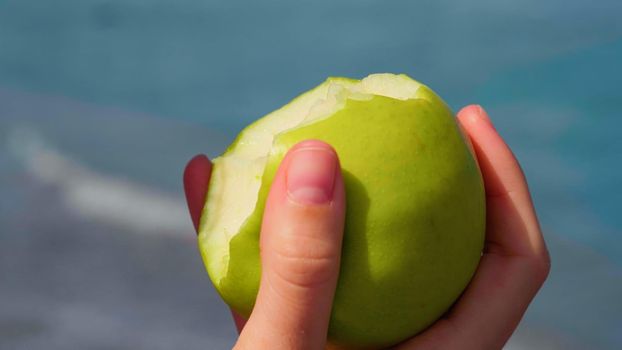 Woman eating apple, fruit. Healthy snack on summer. Close up ripe green apple