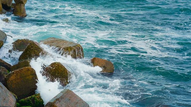 Blue clear sea water on the coastile breaking over rocks