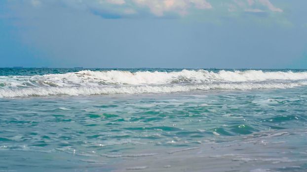 Windy day, agitated, white foamy sea waves. Many big ships floating on the sea, far on the horizon.