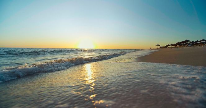 Beautiful scene sunset, tropical beach sea. Tourist destination in Tunisia, Africa. Close up shot of shining waves on seaside.