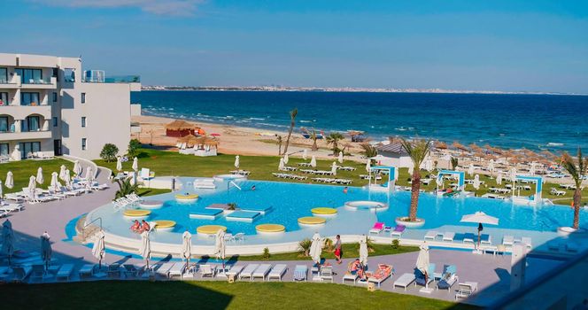 Tunisia, 2022: Hotel on the coast of Tunisia. Beautiful tropical beach front hotel resort with swimming pool, palm trees, perfect vacation.