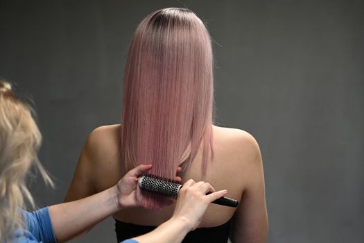 Hairdresser's hands combing model's dyed hair from behind