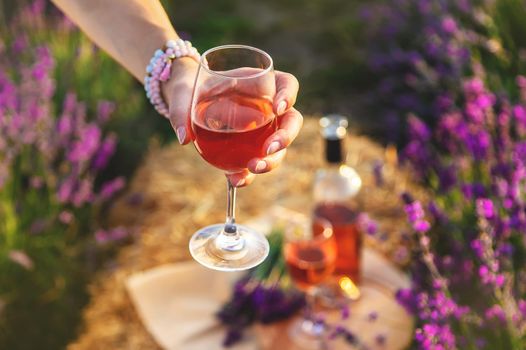 A woman holds wine in glasses. Picnic in the lavender field. Selective focus. nature.